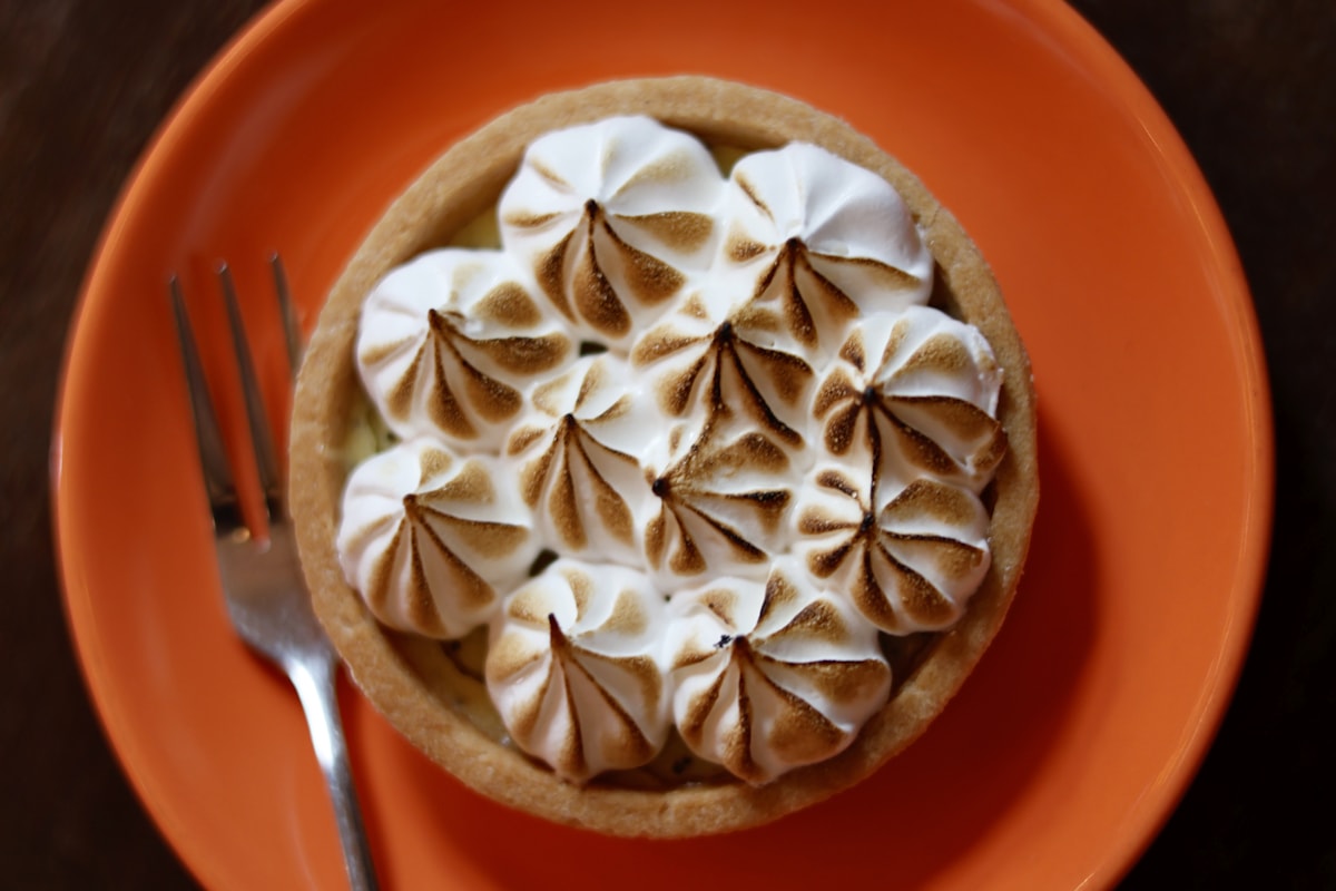 Tarta con merengue tostado sobre plato naranja